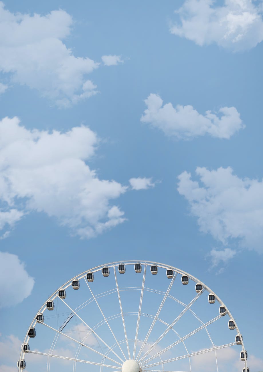 photo of white ferris wheel under white cloudy blue sky